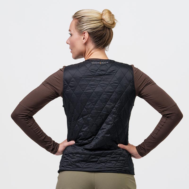 En person båret en sort, quiltet NordicHeat vest over en brun trøje. Vesten ses bagfra, og personen har samlet sit hår i en knold.